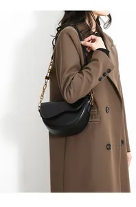 Detailed view of black crescent leather crossbody bag with decorative gold chain strap