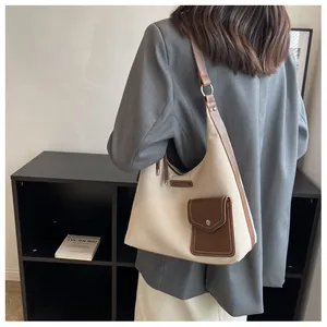 Détail du sac sous le bras en toile et cuir marron porté avec un blazer gris chic