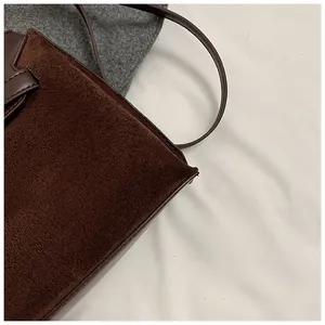 Detailed close-up of dark brown suede and smooth leather texture on a retro satchel bag