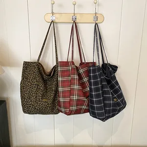 Three large canvas tote bags with leopard and plaid patterns on wooden hooks