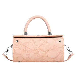 Close-up of pink cylindrical bag featuring hibiscus floral embossing and silver hardware