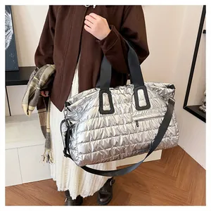 Détail du sac fourre-tout matelassé argenté avec poignées noires et fini métallique