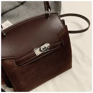 Detail of dark brown Kelly bag with silver hardware lock and suede texture surface