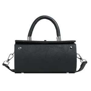 Detailed front view of black cylinder bag with embossed floral pattern and silver hardware