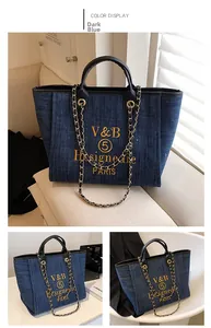 Detail einer dunkelblauen Denim-Tote-Bag mit goldener Kette und Stickerei-Schriftzug