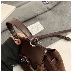Detail of dark brown leather handle and silver metal lock on vintage suede handbag