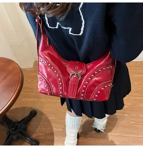 Détail du sac rouge brillant avec des rivets argentés et une fermeture éclair métallique