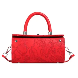 Close-up of bright red cylindrical bag with embossed floral pattern and metal studs