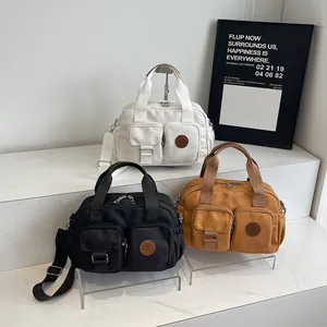 Three minimalist canvas crossbody bags in black, white and camel with front pockets