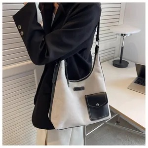 Vue portée d'un sac seau en toile beige avec finitions en cuir noir et poche avant