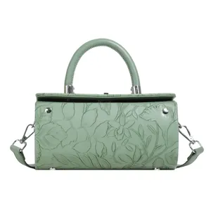 Macro shot of light green cylinder bag showing detailed floral embossed leather texture