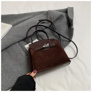 Macro detail of dark coffee suede Kelly style bag with silver clasp on wool coat