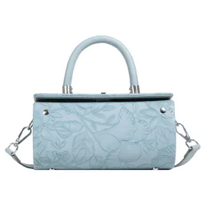 Close-up of light blue cylindrical bag featuring intricate floral embossed leather texture