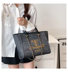 Detailansicht der grauen Tweed-Tasche mit goldener Kette und Stickerei im Lifestyle-Stil