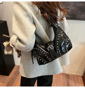 Détail du sac sous le bras en cuir noir brillant avec clous argentés et boucles punk