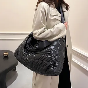 Grand sac fourre-tout matelassé noir en nylon porté par un mannequin en trench-coat beige chic