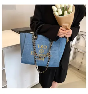 Blue Denim-Tasche mit gelbem Logo-Aufdruck, Lederriemen und goldener Kettenschultergurt