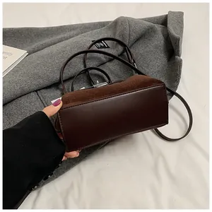 Detail of dark brown Kelly bag featuring suede and smooth leather texture with metal clasp