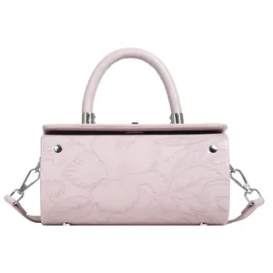 Detail showing 3D floral embossing and silver hardware on a cylinder handbag