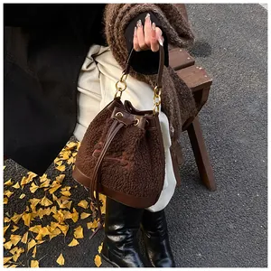 Brown plush bucket bag with drawstring and gold chain handle on a wooden park bench