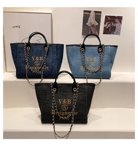 Detailansicht von Denim-Taschen in Blau und Grau mit Goldstickerei und Kettenriemen