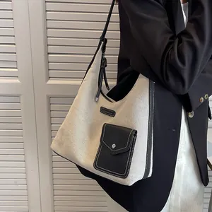 Sac fourre-tout en toile et cuir noir vu de côté sur un mannequin en extérieur