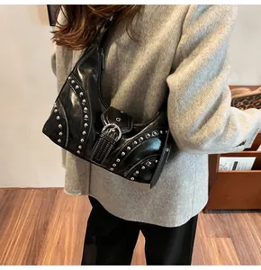 Vue latérale du sac hobo punk noir à rivets argentés porté sur un manteau de laine gris