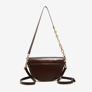 Dark brown saddle crossbody bag with smooth leather finish and stylish gold chain strap