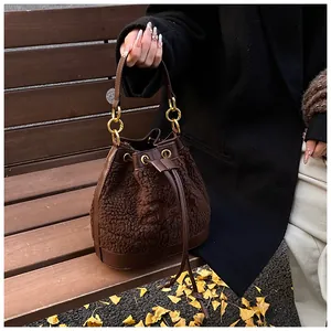 Close-up of brown plush bucket bag with drawstring closure and gold chain handle