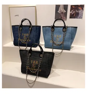 Detailansicht der Denim-Shopper in Schwarz und Blau mit Kettenriemen und Goldstickerei