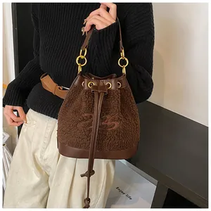 Detail of dark brown plush bucket bag showing embroidery logo and drawstring closure