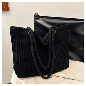 Gros plan du sac cabas en velours côtelé noir montrant la texture côtelée et l'anse