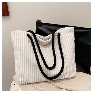 Détail de la texture en velours côtelé blanc et des anses en corde noire du sac