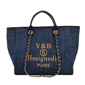 Blaue Denim-Tragetasche mit gelber Bestickung, schwarzen Ledergriffen und Kette