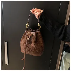 Detail of brown plush bucket bag with leather strap and golden metal ring hardware