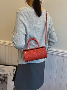 Vintage red cylindrical crossbody bag with embossed floral patterns and a shoulder strap