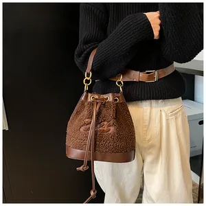 Detail of plush brown shearling bucket bag with leather strap and drawstring closure