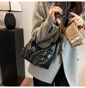 Détail du sac hobo en cuir noir avec rivets argentés et fermetures éclair décoratives
