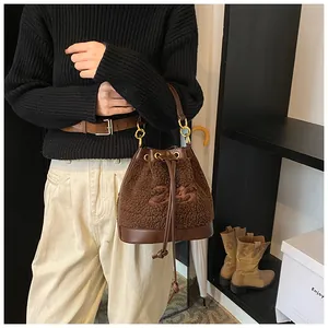 Detail of plush brown bucket bag with embroidered number 24 and gold metal ring