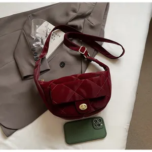 Detail of dark red quilted crossbody bag with golden metal twist lock and wide strap
