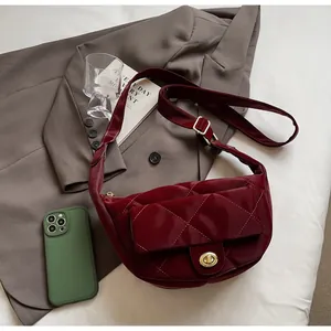 Detail of wine red patent leather dumpling bag with diamond quilting and gold twist lock