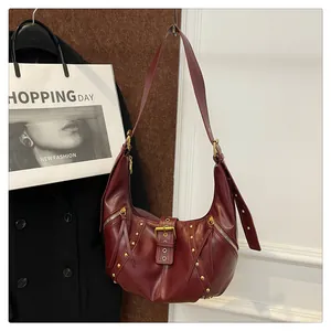 Detail of burgundy half-moon bag featuring gold rivets and vintage belt buckle design