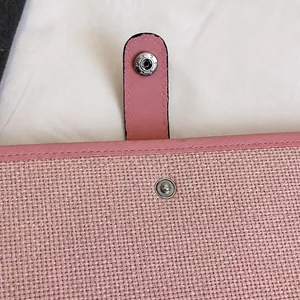 Detail of pink woven texture file bag with durable silver snap button and stitching