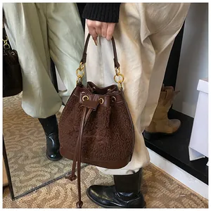 Detail of plush bucket bag featuring shearling texture, leather drawstring and gold hardware