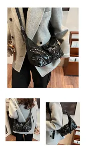 Détail du sac à bandoulière noir en forme de croissant avec rivets argentés et pompon
