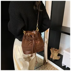Detail of plush bucket bag with drawstring closure and leather strap on model