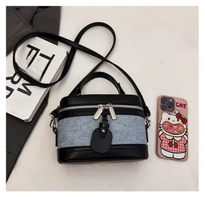 Close-up of contrast bucket bag featuring blue denim and black leather with silver dual zippers