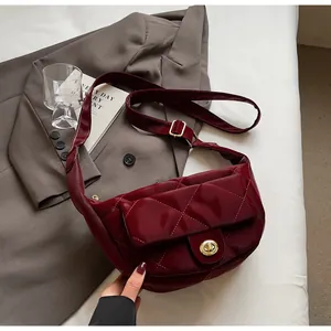 Close-up of wine red quilted patent leather saddle bag with golden twist lock detail