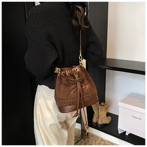 Detail of dark brown plush bucket bag with leather base and drawstring closure