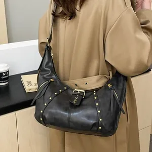 Vintage black leather dumpling bag with gold studs and tassels worn with a khaki trench coat